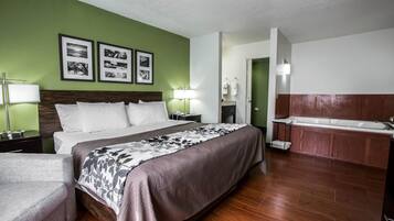 Habitación de hotel con una cama grande, zona de estar, baño con bañera y cuadros en la pared.