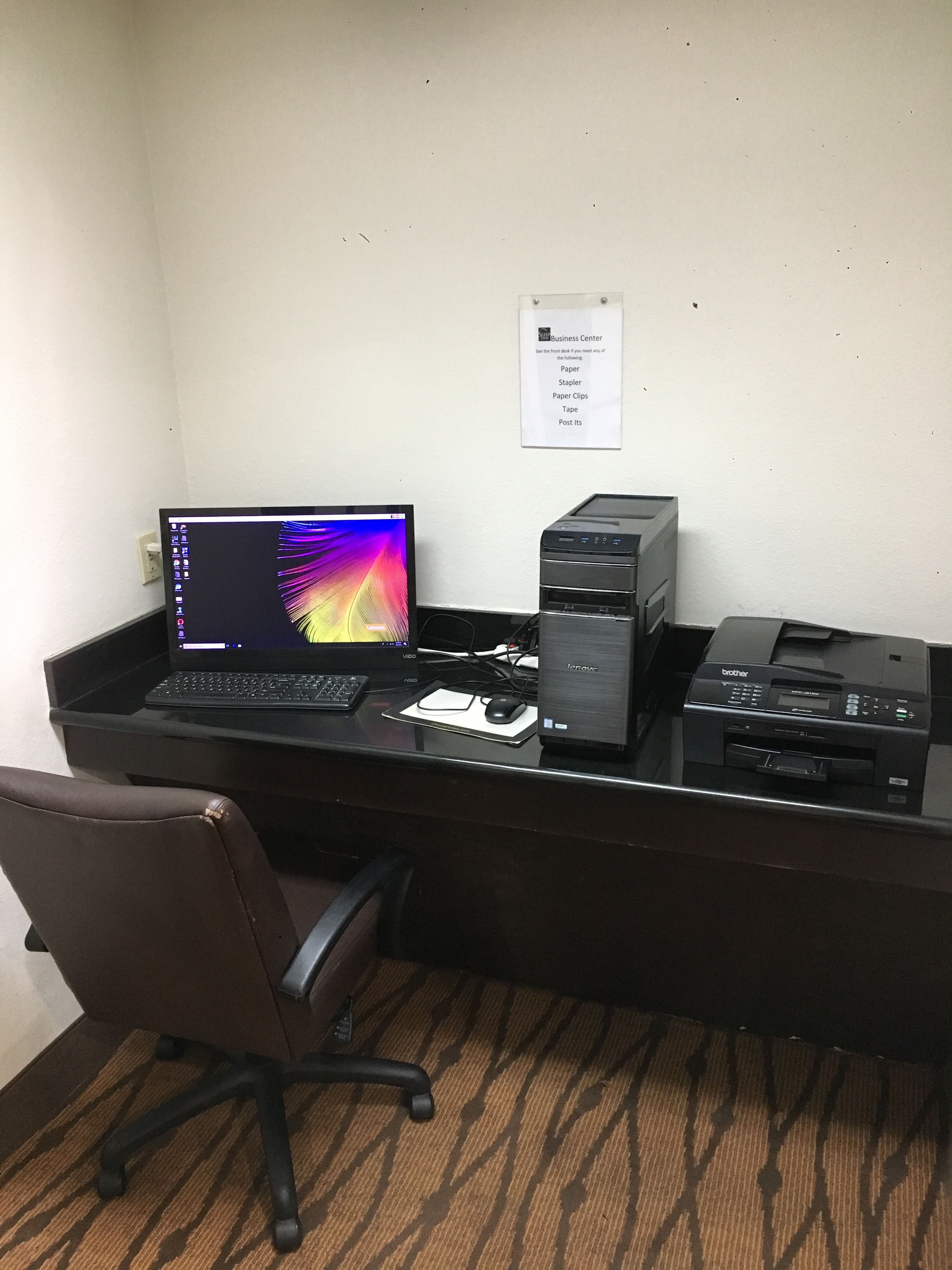 A desk with a laptop, a desktop computer, and a printer. There is a chair in front of the desk.