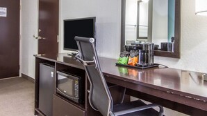 Hotelkamer met een bureau, een televisie, een magnetron, een koffiezetapparaat en een spiegel.