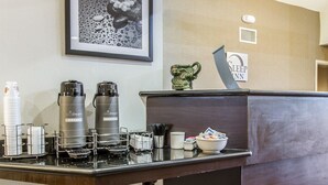 Een hotel receptie met een koffiehoek, een ingelijste kunstwerk aan de muur en een bord met de tekst 'SLEEP'.