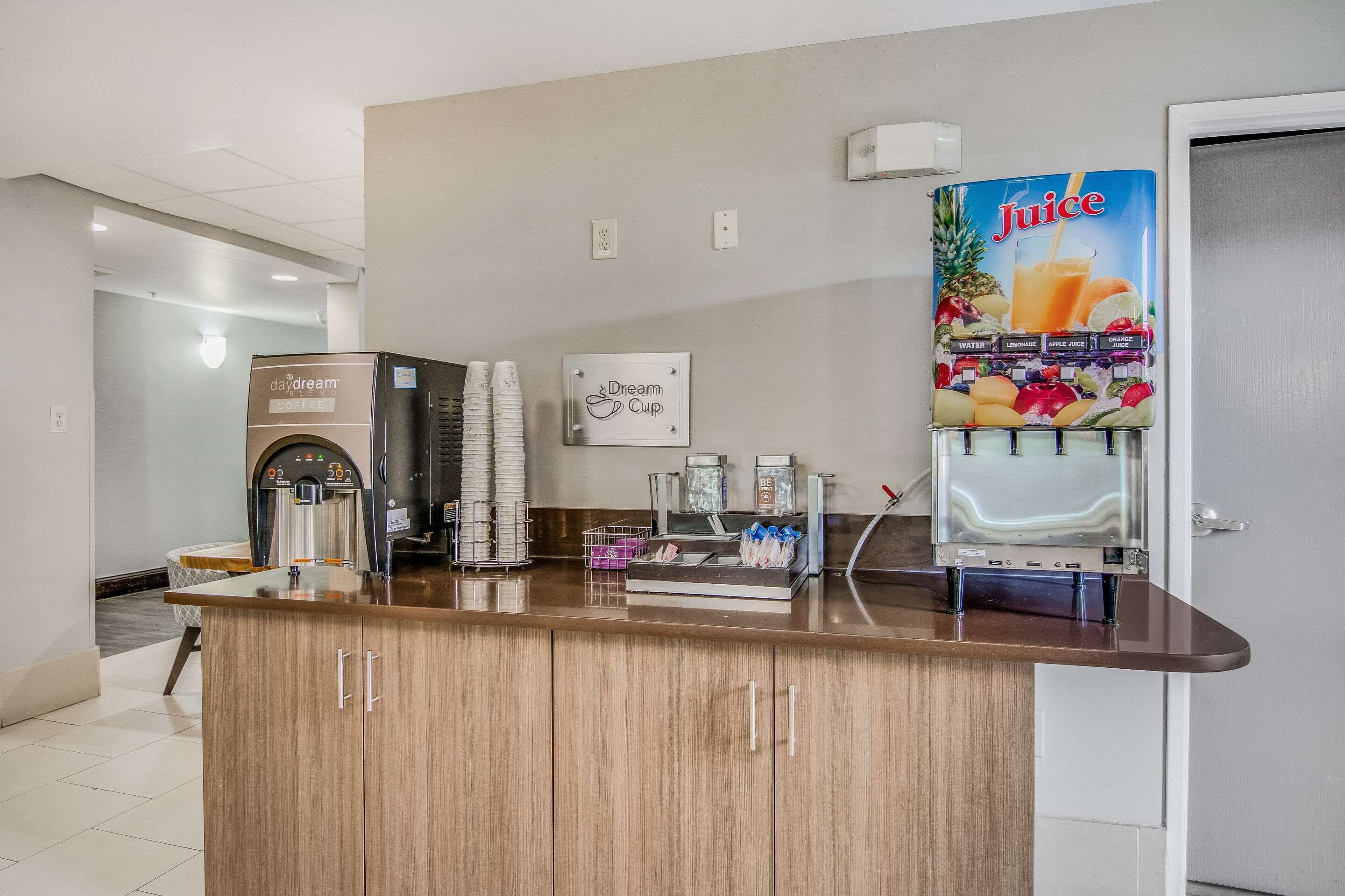 A reception area with a coffee machine, a juice dispenser, and a sign for 'Dream Cup'.