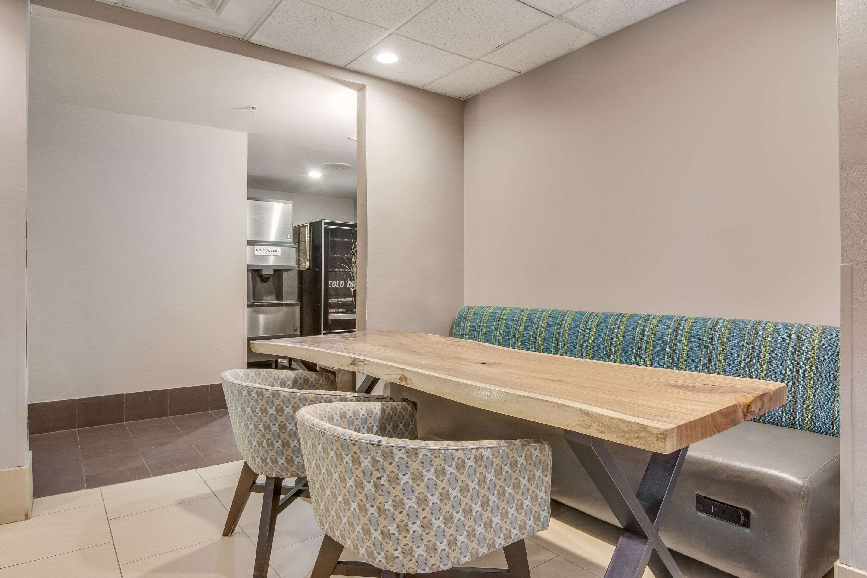 A modern kitchen with a wooden table, two patterned chairs, and a blue-striped sofa.