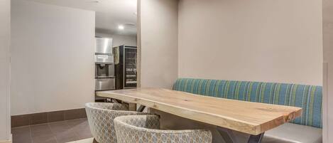 A modern kitchen with a wooden table, two patterned chairs, and a blue-striped sofa.