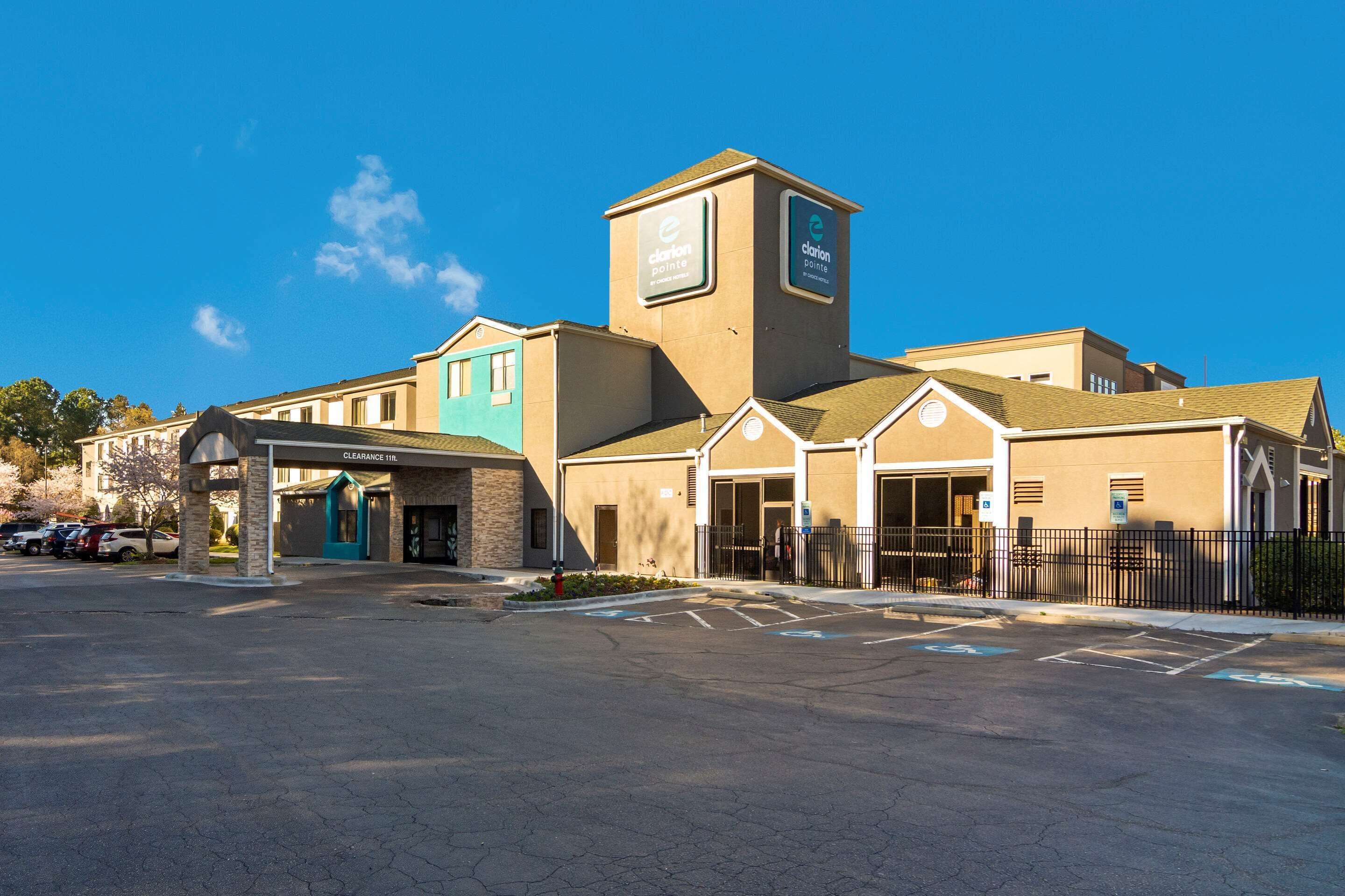 A hotel with a clear entrance, a parking lot, and a small garden area.