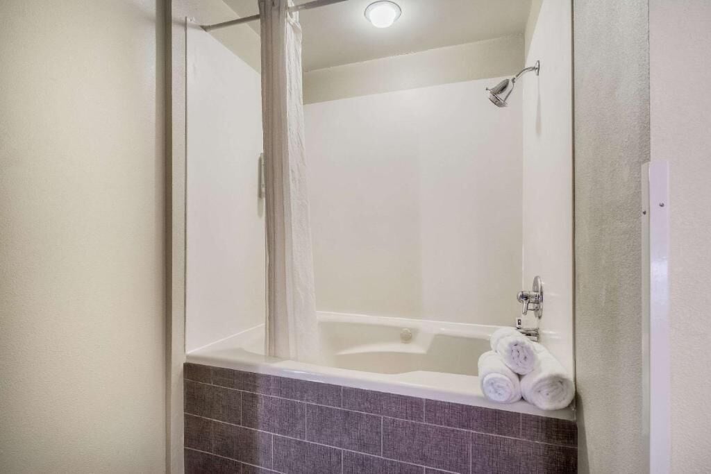 A modern bathroom with a bathtub, shower, and a towel rack with towels.