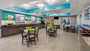 Un restaurant moderne aux murs de couleur turquoise, avec un comptoir, ainsi que plusieurs tables et chaises.