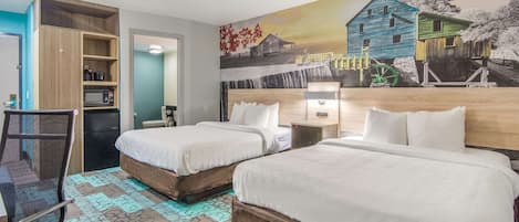 A hotel room with two beds, a desk, a chair, a microwave, and a shelf with items.