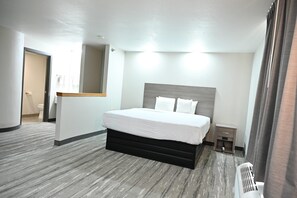 A hotel room with a large bed, a bedside table, a small nightstand, and a radiator.