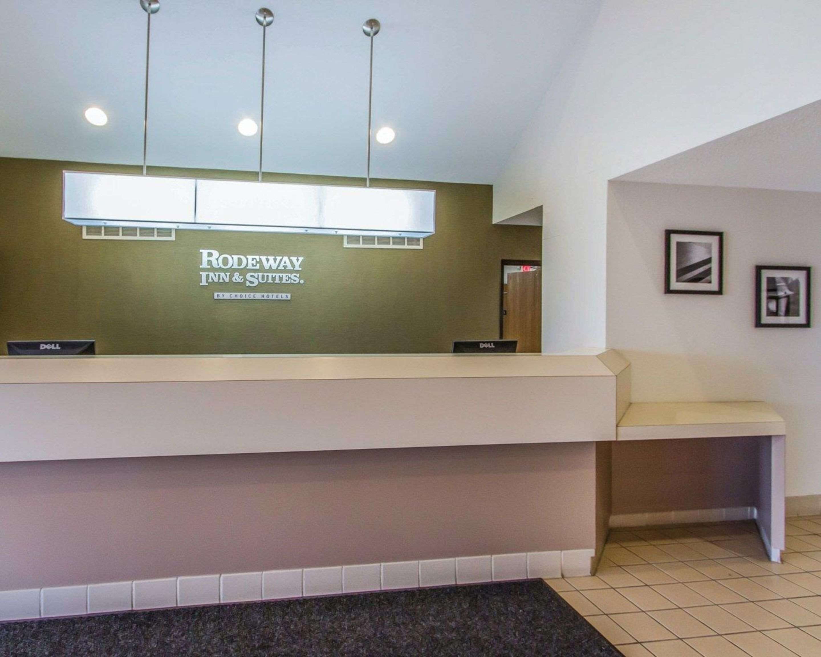 Una recepción con el rótulo de Rodeway Inn & Suites by Choice Hotels, una computadora Dell y un cuadro en la pared.