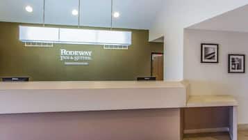 Una recepción con el rótulo de Rodeway Inn & Suites by Choice Hotels, una computadora Dell y un cuadro en la pared.