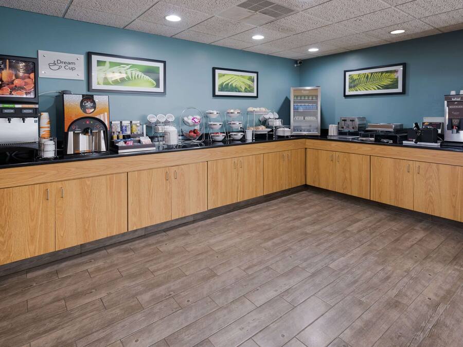 A coffee shop counter with a fruit juice dispenser, a coffee machine, and a display of coffee cups.