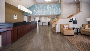 A hotel lobby with a reception desk, seating area, staircase, and a sign indicating the name of the hotel. - Sleep Inn & Suites Port Clinton (Port Clinton)