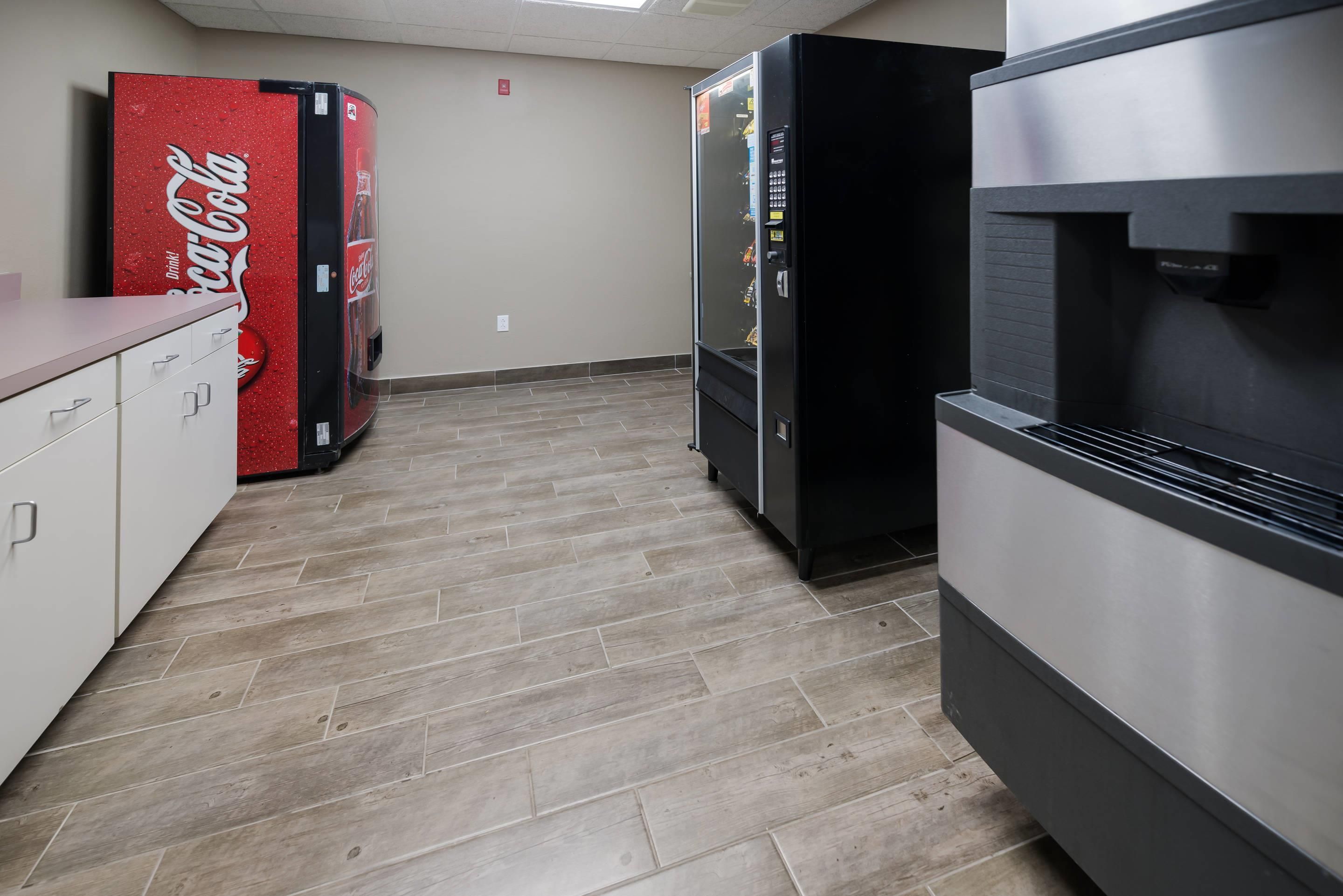 Una cocina con refrigerador, microondas y máquina expendedora.