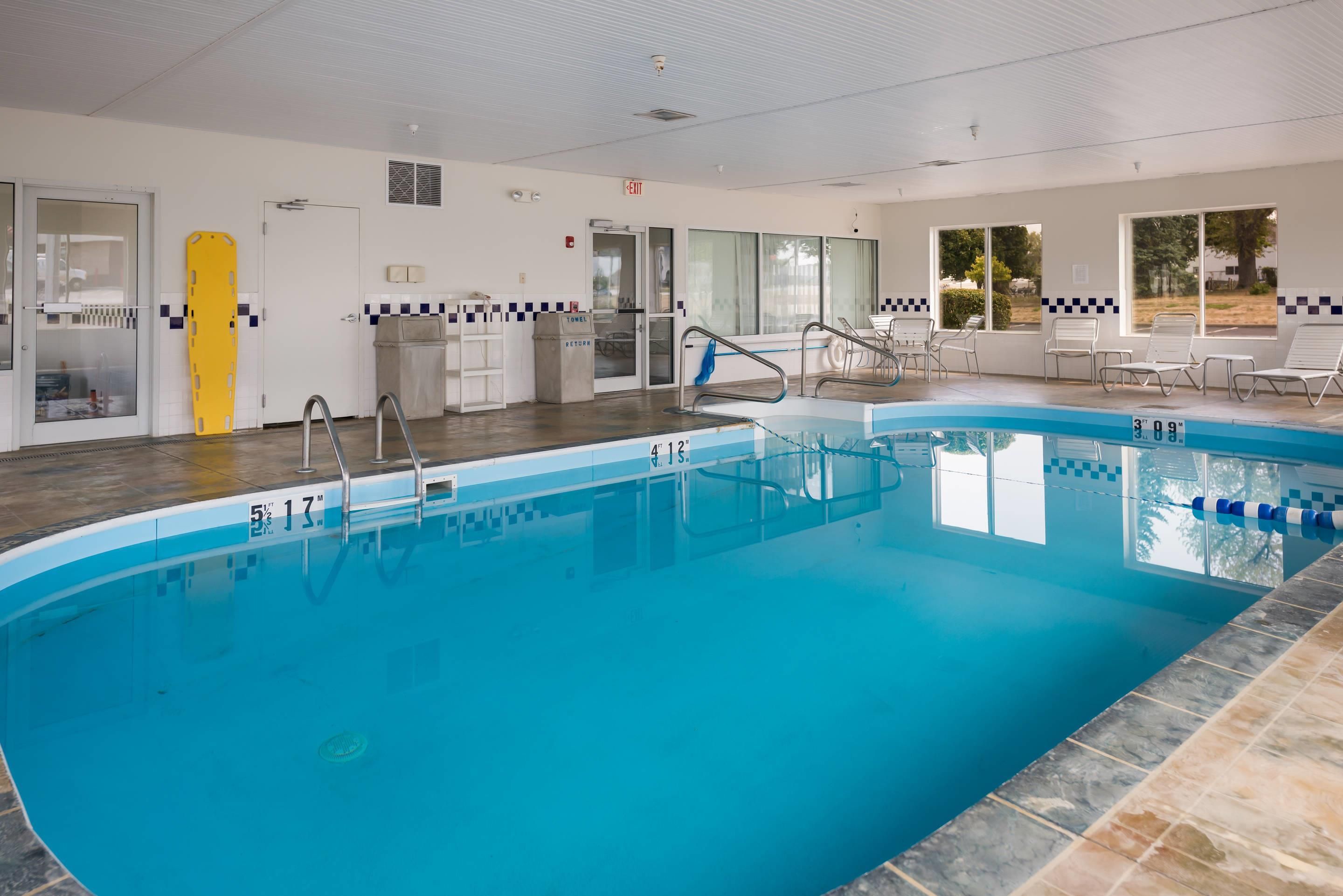 A swimming pool with clear water, marked depth lines, and a lifeguard chair.