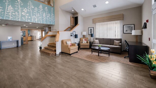 A spacious living area with a staircase, a sofa, a coffee table, and a reception desk. - Sleep Inn & Suites Port Clinton (Port Clinton)