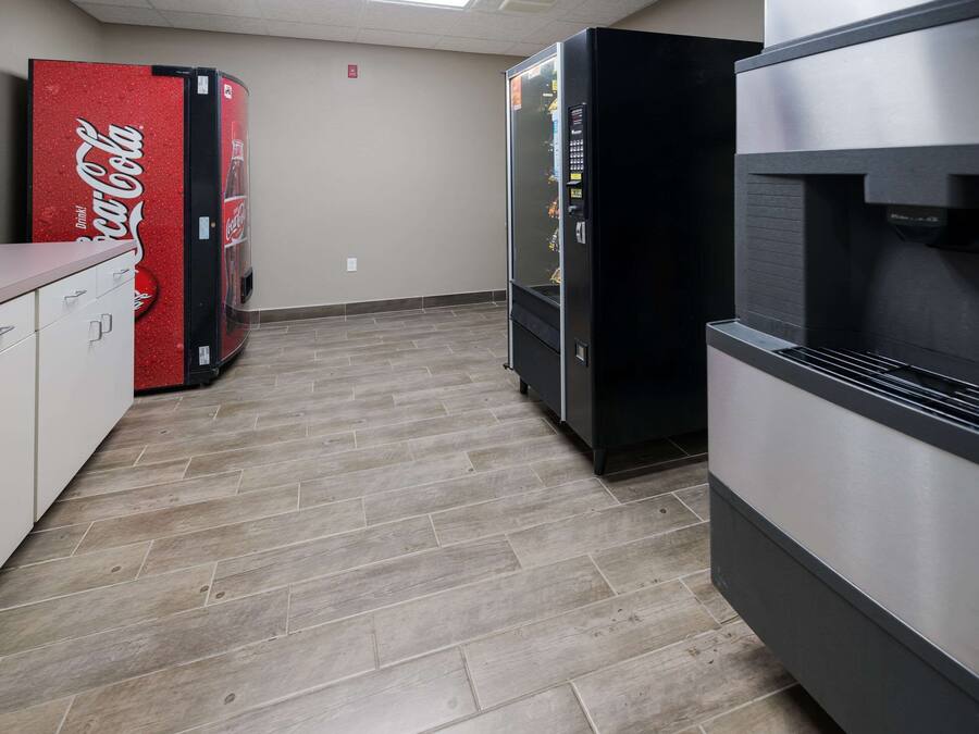 A kitchen with a refrigerator, a microwave, and a Coca-Cola vending machine.