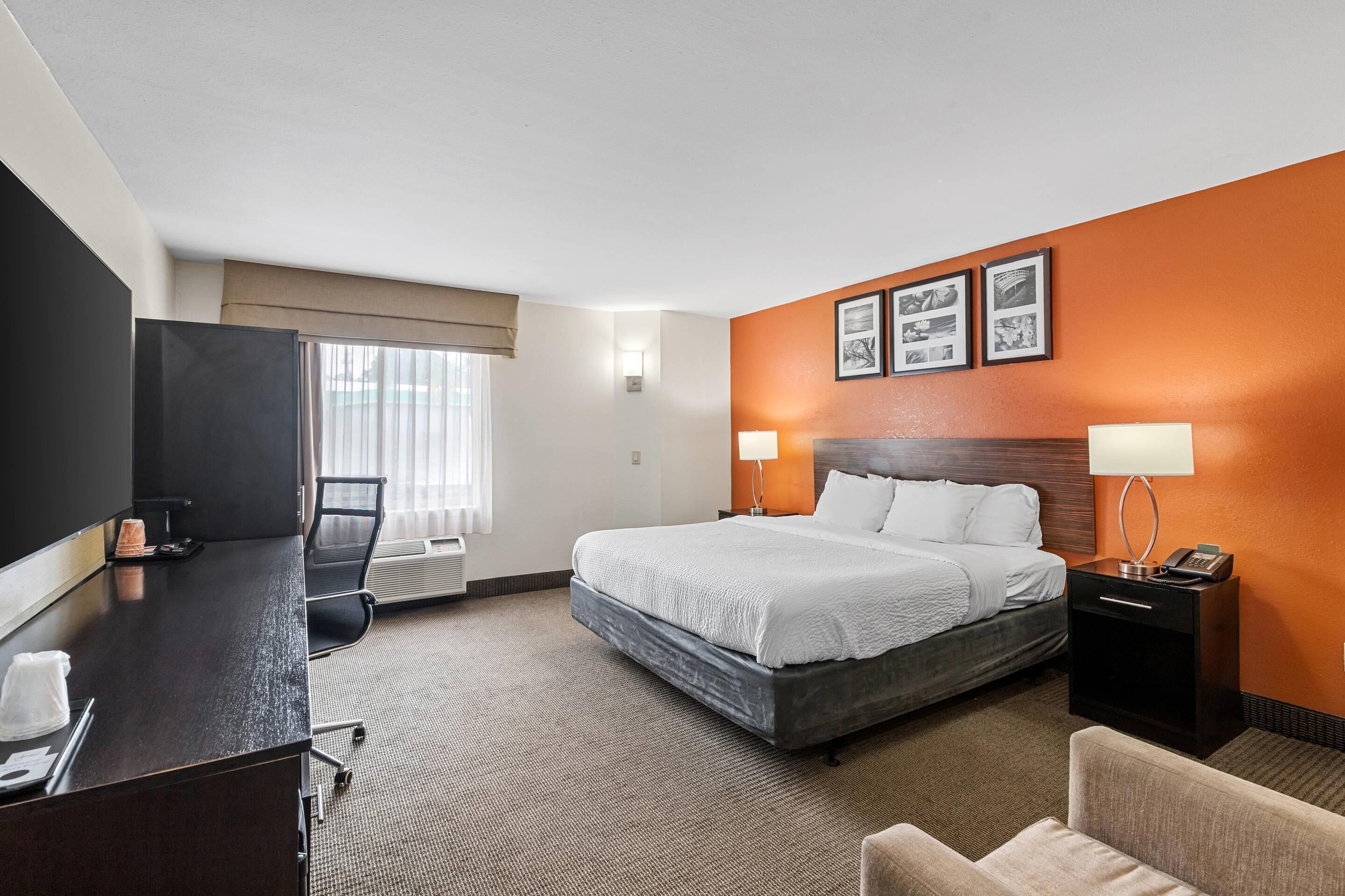 Una habitación de hotel con cama, escritorio, silla y televisor.