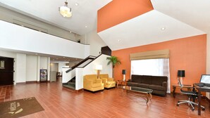 A spacious living area with a staircase, a sofa, a coffee table, and a desk with a computer.