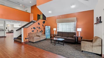 A hotel lobby with a staircase, sofas, a coffee table, and a reception desk.