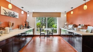 A modern kitchen with a central island, two chairs, and a large window.