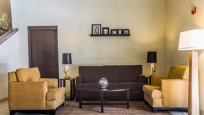 A living room with a sofa, two armchairs, a coffee table, and a rug. There are picture frames on the wall and two lamps on side tables. - Sleep Inn Columbia Airport (West Columbia)