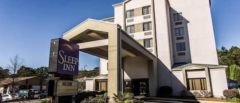 Un hotel Sleep Inn con un letrero grande, una entrada techada y un estacionamiento.