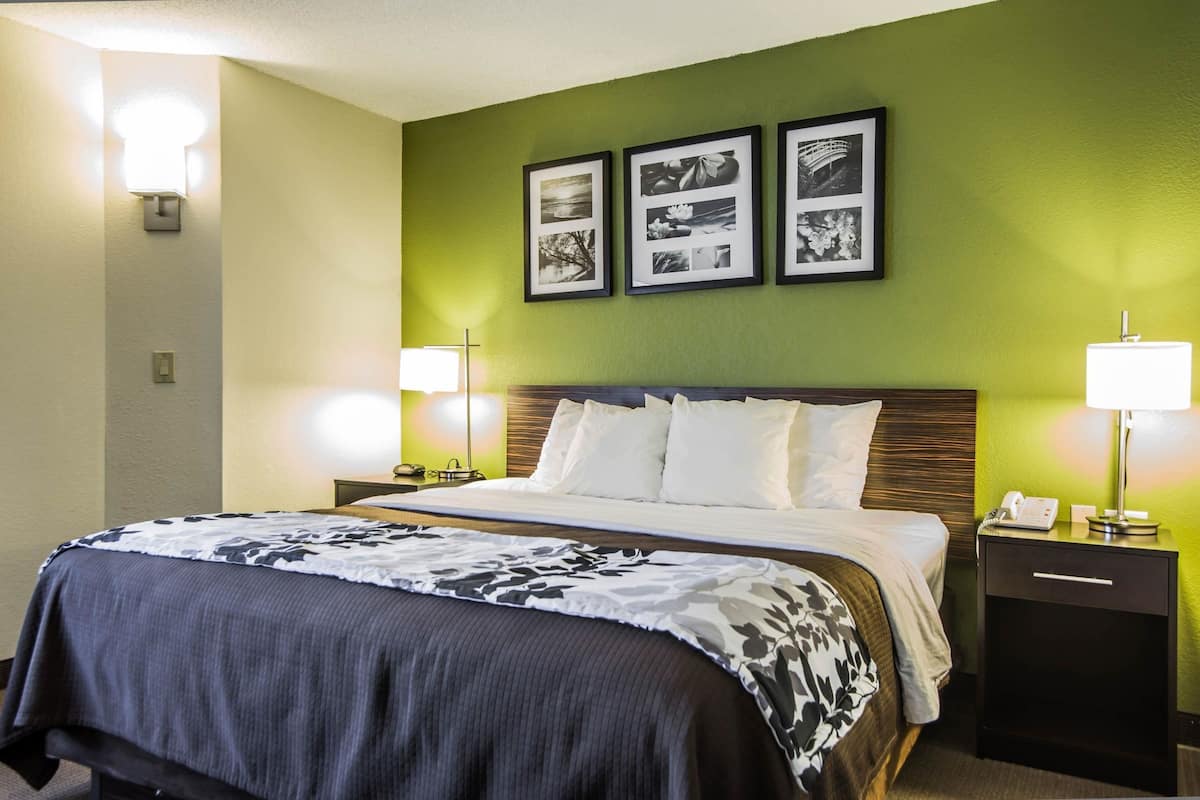 A hotel room with a bed, two bedside tables, a nightstand, and three framed pictures on the wall.