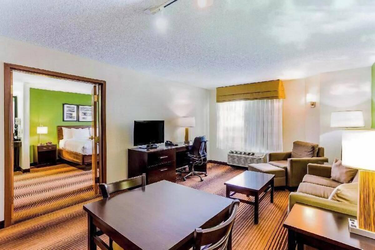 A hotel room with a bed, desk, TV, and seating area.
