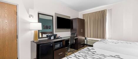A hotel room with a bed, a desk with a computer, a TV, and a wardrobe.