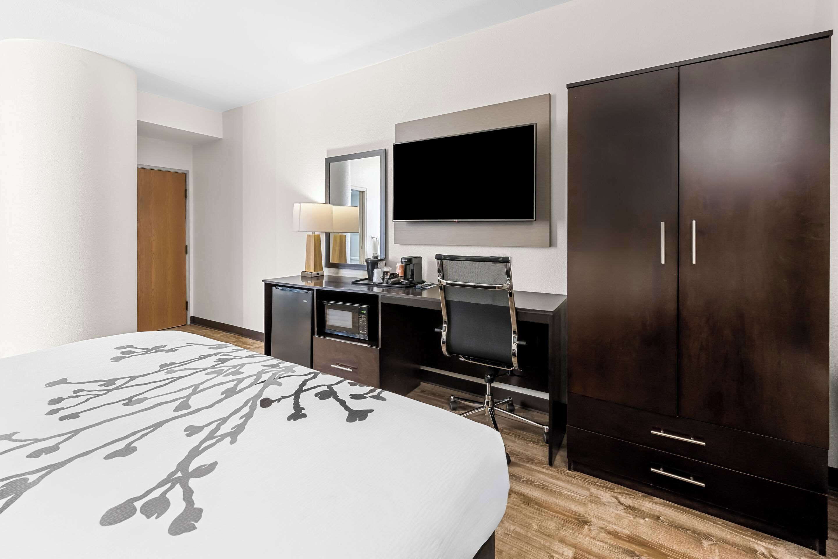 A hotel room with a bed, a desk, a TV, and a wardrobe.