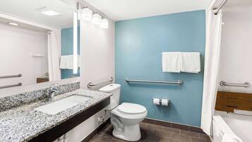 Un baño moderno con lavamanos de granito, inodoro blanco y bañera.