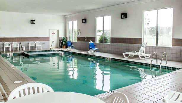 An indoor swimming pool with clear water, tiled walls, and several lounge chairs. - Rodeway Inn Abbotsford (Colby)