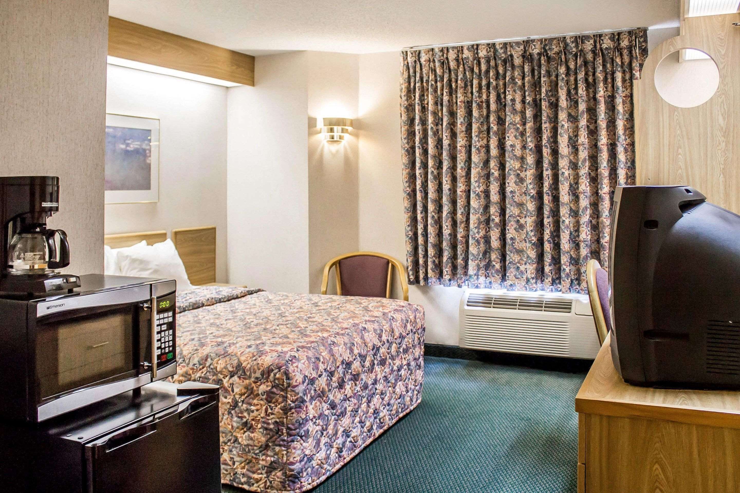 Ein Hotelzimmer mit einem Bett, einem Schreibtisch mit Fernseher, einer Kaffeemaschine und einer Klimaanlage.