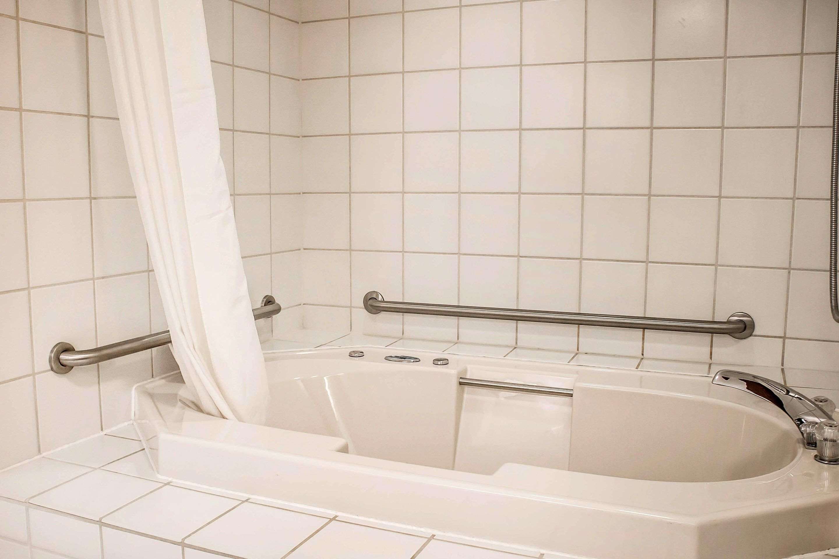 Ein Badezimmer mit Badewanne, Duschvorhang und einer Haltestange.