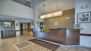 A hotel reception area with a modern design, featuring a reception desk, a welcome mat, and framed pictures on the walls.