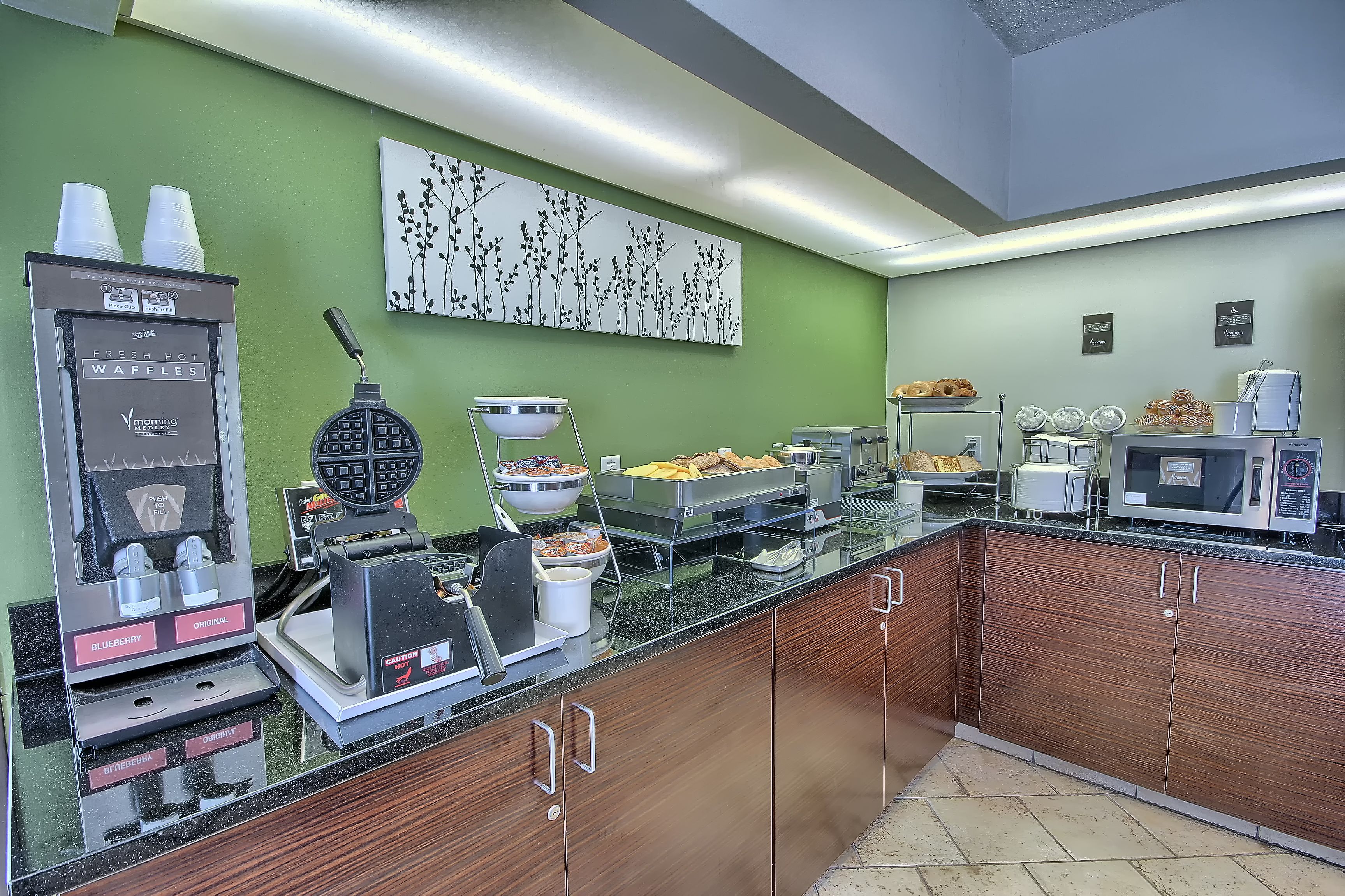 Un buffet de petit-déjeuner comprenant des appareils à gaufres, un coin café et un four à micro-ondes.