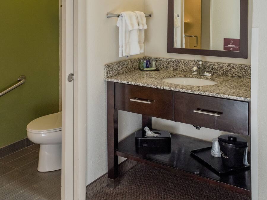 A bathroom with a toilet, a sink with a mirror, and a towel rack.