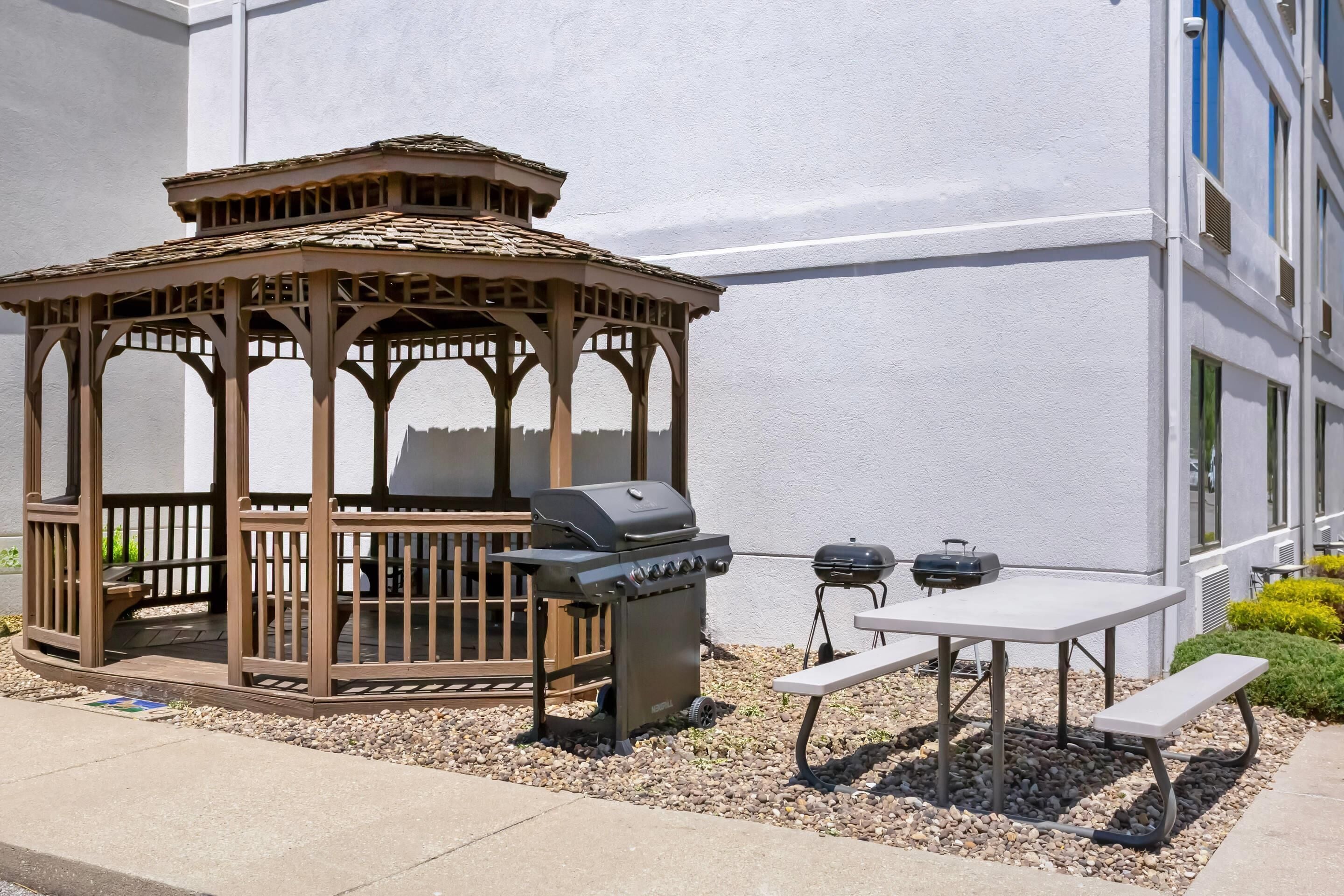 A gazebo with a grill and a table with benches.