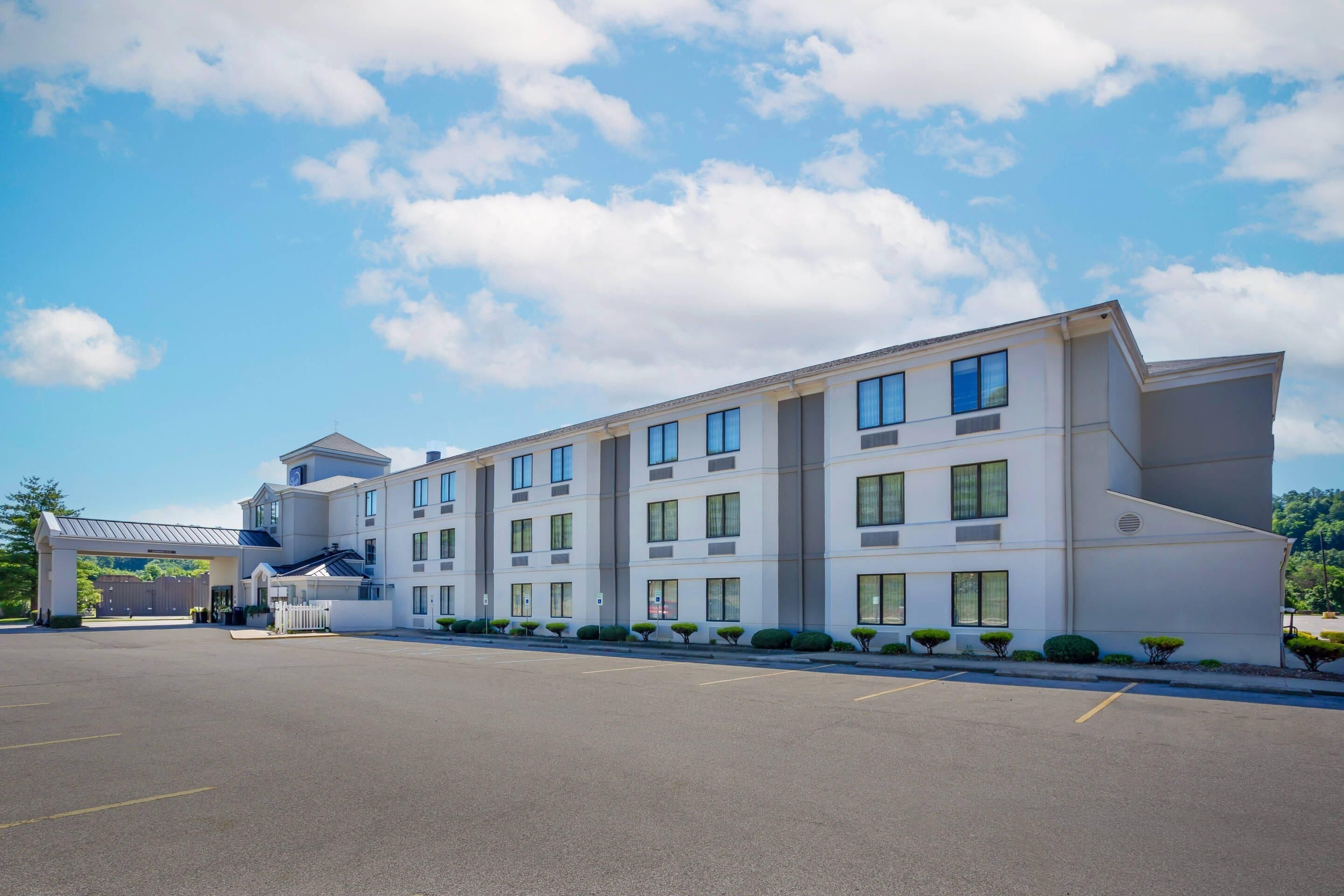 A modern hotel with a parking lot, multiple floors, and a flat roof.