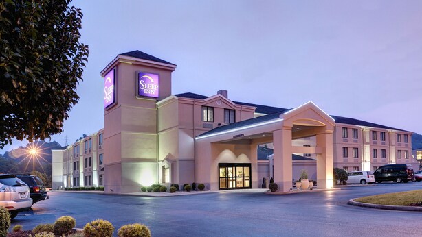 A hotel with a prominent 'Sleep Inn' sign, a covered entrance, and a parking lot with several cars.