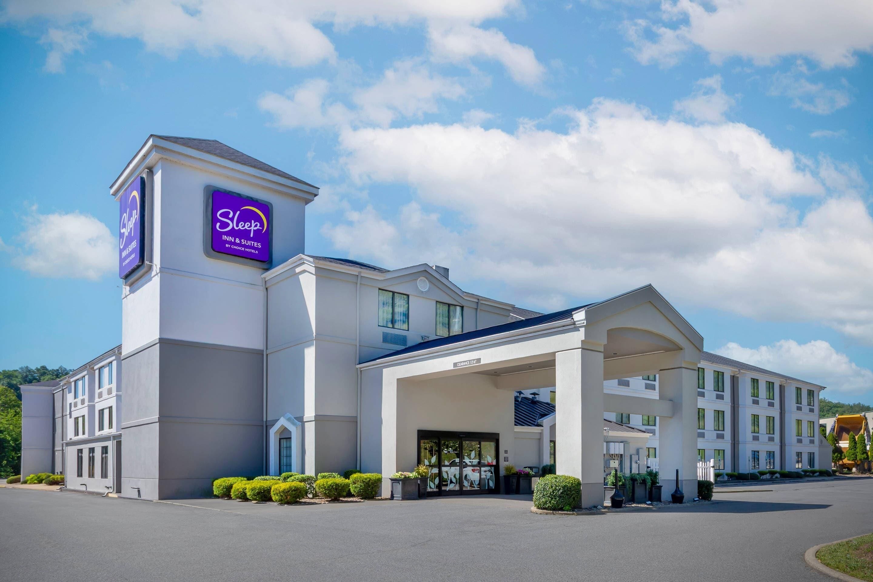 Un hôtel Sleep Inn & Suites au design moderne, avec une entrée imposante et une vue dégagée sur le ciel.