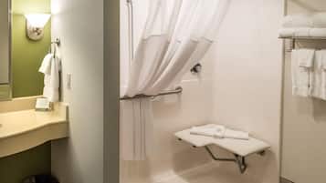 A bathroom with a shower, a sink, a towel rack, and a small shelf with a towel.