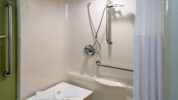 A shower area with a grab bar, a handheld showerhead, and a small white shelf with a towel.