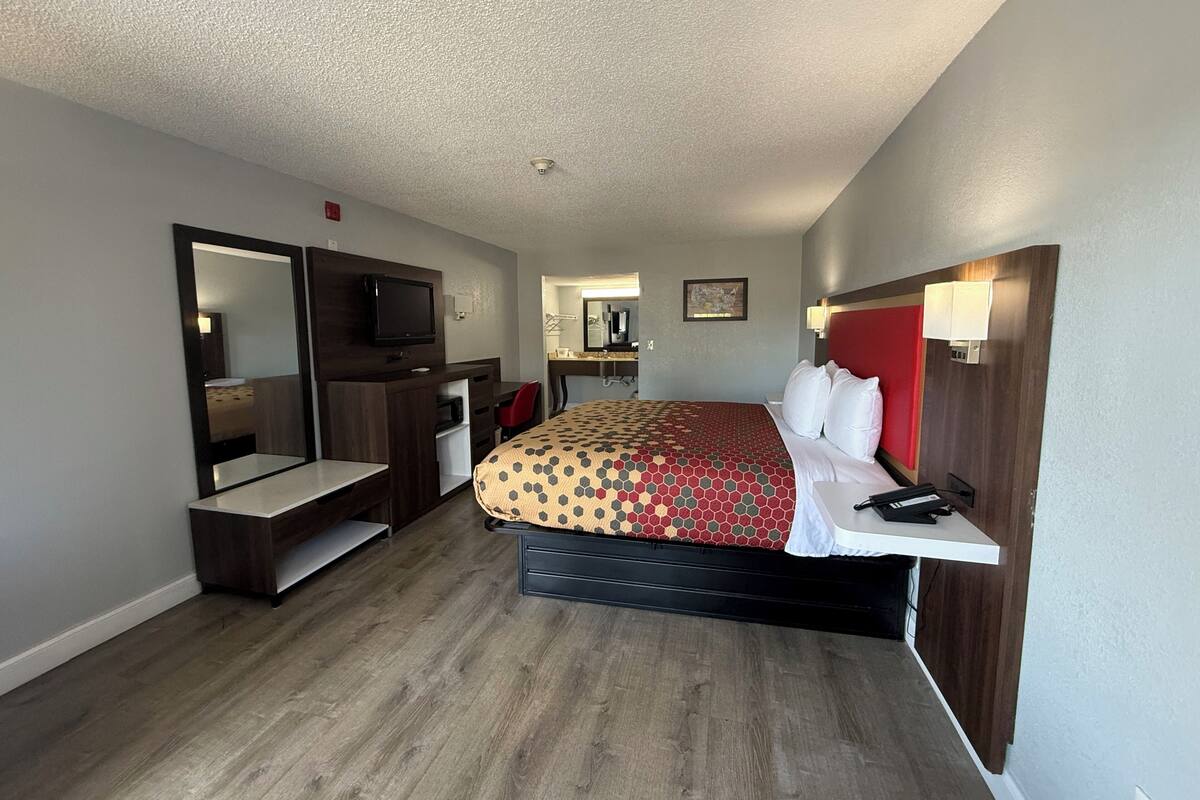 A hotel room with a bed, a TV, a desk, and a mirror.