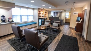 A modern hotel lobby with seating areas, a reception desk, and a minibar. - TownePlace Suites by Marriott Gahanna (Columbus)
