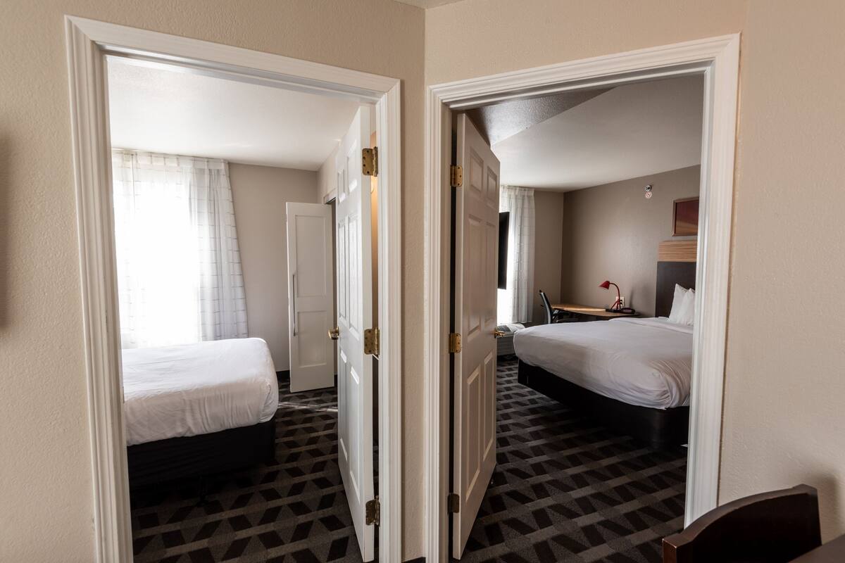 Une chambre d’hôtel avec deux lits, un bureau et une chaise.