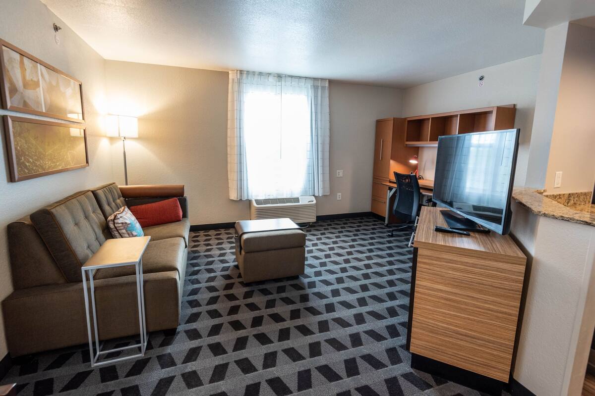 Une chambre d’hôtel équipée d’un canapé, d’une petite table, d’une télévision et d’un coin cuisine.
