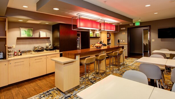 Un hall de hotel con zona de bar, asientos y mostrador de recepción.
