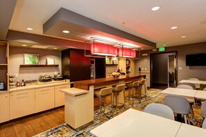 Un hall de hotel con zona de bar, asientos y mostrador de recepción.