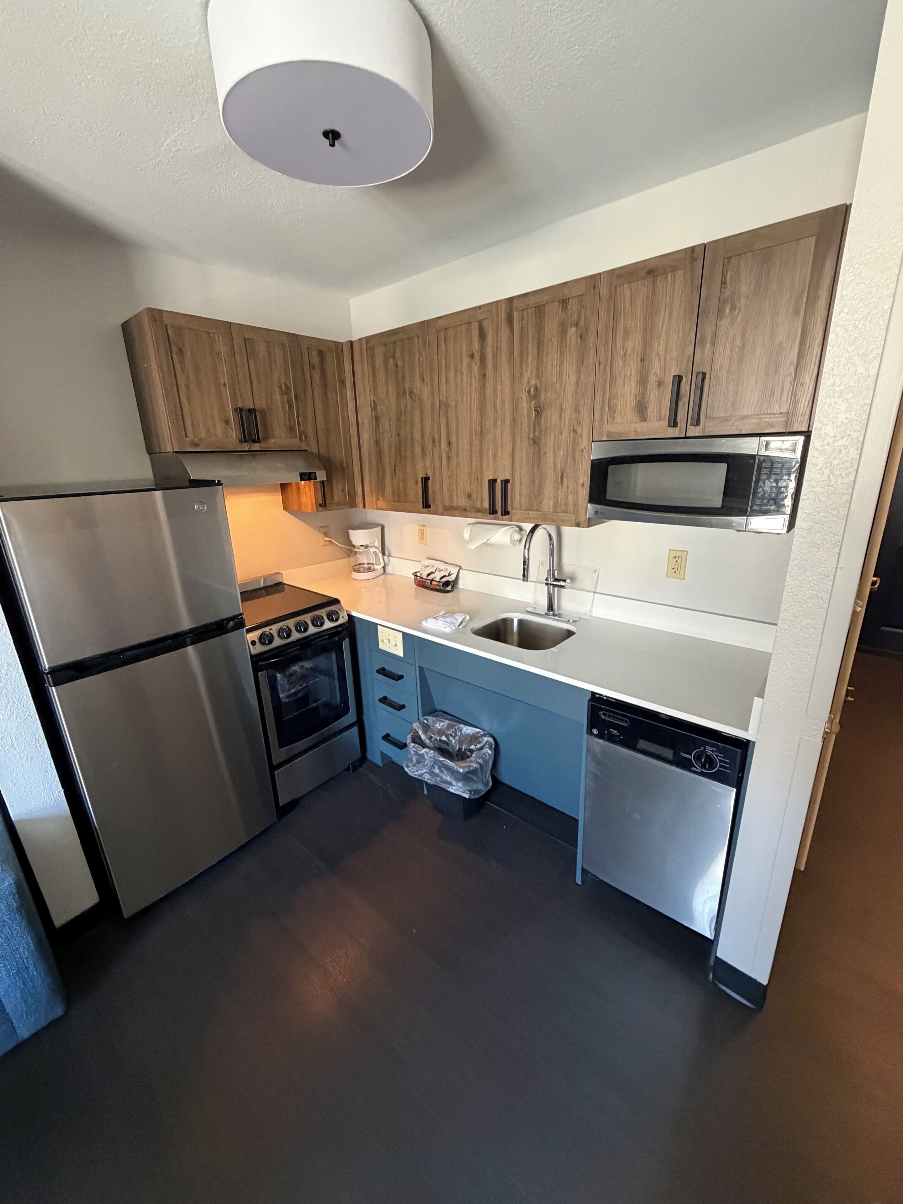 Une cuisine moderne avec des meubles en bois, des appareils électroménagers en acier inoxydable et un four à micro-ondes encastré.